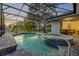 Screened-in pool and hot tub with brick surround and view of pond and palms at 634 Woodford Dr, Debary, FL 32713