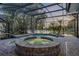 Screened-in pool and hot tub with brick surround and view of pond at 634 Woodford Dr, Debary, FL 32713