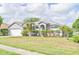 Inviting home with lush landscaping, including a palm tree, gray stucco, and attached two-car garage at 6403 Adrianne Ct, Port Orange, FL 32128