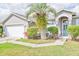 Close-up view of a gray stucco home showcasing an arched entryway, well-kept lawn, and two-car garage at 6403 Adrianne Ct, Port Orange, FL 32128