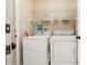 A practical laundry room with white washer and dryer, and storage shelves for convenience at 6403 Adrianne Ct, Port Orange, FL 32128