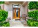 Inviting front porch showcasing a decorative bench, small side table, and lush landscaping around the entrance at 6436 Longlake Dr, Port Orange, FL 32128