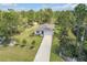Picturesque aerial view of a single-story home with an attached garage, long driveway, and lush landscaping in a serene setting at 703 Volco Rd, Edgewater, FL 32141