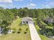 Aerial view of a well-maintained property with a single-story home, attached garage, large lawn, and mature trees at 703 Volco Rd, Edgewater, FL 32141