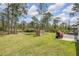 Spacious backyard with lush grass, mature trees, and an outdoor seating area at 703 Volco Rd, Edgewater, FL 32141