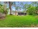Large backyard with green lawn, a screened-in porch, and mature trees at 795 Sugar Cane Ln, Port Orange, FL 32129