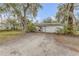 Exterior view of the detached garage with gravel drive and mature tree providing shade at 801 Canal St, New Smyrna Beach, FL 32168