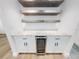 Close-up of the modern bar area features a wine fridge, shelving, granite countertops, and white cabinets at 808 Rosalia Dr, Sanford, FL 32771