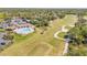 Aerial view of a golf course, pool, and clubhouse on a sunny day at 1100 Loch Linnhe Ct, New Smyrna Beach, FL 32168
