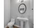 Small bathroom featuring a pedestal sink, toilet, and a round mirror at 1100 Loch Linnhe Ct, New Smyrna Beach, FL 32168