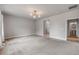 Living room featuring three windows, carpet, and statement chandelier at 1100 Loch Linnhe Ct, New Smyrna Beach, FL 32168