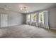 Bright living room featuring three windows, plush carpet, and a door at 1100 Loch Linnhe Ct, New Smyrna Beach, FL 32168