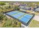 Aerial view of community tennis and pickle ball courts in a tropical landscape at 1100 Loch Linnhe Ct, New Smyrna Beach, FL 32168