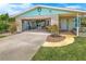 Home exterior featuring a stone facade, open garage, well-manicured lawn, and a colorful front door at 124 Anchor Dr, Ponce Inlet, FL 32127