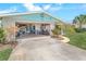 Home exterior featuring a stone facade, open garage, well-manicured lawn and flower bushes at 124 Anchor Dr, Ponce Inlet, FL 32127