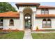 Front exterior featuring white stucco, red roof, arched entryway with columns, and well-kept landscaping at 2813 Ballard Ave, Orlando, FL 32833