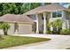 Inviting home featuring an attached three-car garage, large windows, decorative columns and manicured landscaping at 305 Country Circle E Dr, Port Orange, FL 32128