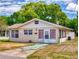 Exterior elevation of a one-story home featuring a cozy front porch, lush green trees, and a driveway at 310 Legion Pl, Port Orange, FL 32129