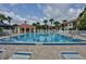 Community pool with a depth of six feet and lounge chairs under a cloudy blue sky at 445 Bouchelle Dr # 301, New Smyrna Beach, FL 32169