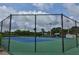 Fenced in tennis court with blue and green surface, surrounded by lush trees at 445 Bouchelle Dr # 301, New Smyrna Beach, FL 32169
