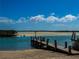 Scenic view of a wooden dock leading to serene waters, with a sandy beach and clear blue skies at 4752 S Atlantic Ave # 1, Ponce Inlet, FL 32127