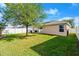 A lush backyard featuring a beautiful lawn, mature tree, privacy fence, and sliding glass doors to the home at 5304 Cordgrass Bend Ln, Port Orange, FL 32128