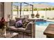 A comfortable outdoor seating area with a wicker sofa, pillows, and plants, next to a screened pool and hot tub at 6068 Spruce Point Cir, Port Orange, FL 32128