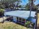 Aerial view of the home showing its layout, screened lanai, metal roof, landscaping, and surrounding yard at 650 S Pine St, New Smyrna Beach, FL 32169