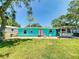 A vibrant home has a brick patio, lush lawn, outdoor bar, and brightly painted doors and trim at 650 S Pine St, New Smyrna Beach, FL 32169