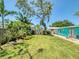 Lush backyard featuring mature trees, shrubs, flowers and a small patio outside the house at 650 S Pine St, New Smyrna Beach, FL 32169