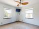 Bright bedroom featuring two windows, a ceiling fan, and a wall-mounted TV for comfortable viewing at 650 S Pine St, New Smyrna Beach, FL 32169