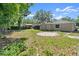 View of the backyard with partially overgrown landscaping and mature trees at 126 Brandy Hills Dr, Port Orange, FL 32129
