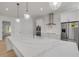 A spacious kitchen with a marble countertop island, stainless steel refrigerator, and pendant lighting at 1371 Melonie Trl, New Smyrna Beach, FL 32168