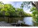 Lakeside wooden dock with ladder leading to a calm river surrounded by lush foliage at 1787 Earhart Ct, Port Orange, FL 32128