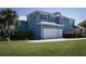 Side view of a blue two-story home with a large two car garage and well-manicured lawn at 1787 Earhart Ct, Port Orange, FL 32128