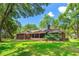 Back exterior showing a screened patio, brick, and well kept lawn at 32030 Dewberry Ln, Sorrento, FL 32776