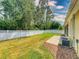 Grassy backyard featuring white fence, patio area with decorative rock, and view of trees at 3455 Pegaso Ave, New Smyrna Beach, FL 32168