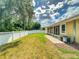 Grassy backyard featuring white fence, patio area with decorative rock, and view of trees at 3455 Pegaso Ave, New Smyrna Beach, FL 32168