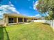 Expansive backyard view showcasing well-maintained lawn, patio, and white fencing for added privacy at 3455 Pegaso Ave, New Smyrna Beach, FL 32168