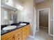 Bathroom featuring dual sinks, wood cabinets, black countertops, and a walk-in closet at 3455 Pegaso Ave, New Smyrna Beach, FL 32168