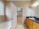 Bathroom boasts a wooden vanity with granite countertops, a soaking tub, and leads to the bedroom at 3455 Pegaso Ave, New Smyrna Beach, FL 32168