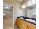 Bathroom featuring dual sinks, wood cabinets, black countertops, with a view to the main bedroom at 3455 Pegaso Ave, New Smyrna Beach, FL 32168