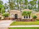 Charming single-story home featuring a tile roof, stone accents, and a well-manicured lawn with palm trees at 3455 Pegaso Ave, New Smyrna Beach, FL 32168