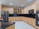 Modern kitchen with wooden cabinets, black countertops, stainless steel appliances, and tile flooring at 3455 Pegaso Ave, New Smyrna Beach, FL 32168