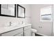 Bathroom featuring double sinks, gray cabinets, two framed mirrors, and a window for natural light at 377 Palm Dr, New Smyrna Beach, FL 32168