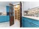 Bright kitchen featuring blue cabinets, mosaic backsplash, and a walk-in pantry with decorative wooden doors at 6260 S Atlantic Ave, New Smyrna Beach, FL 32169