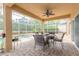 Covered brick patio with a ceiling fan and a dining table, next to a pool and pond at 6950 Vintage Ln, Port Orange, FL 32128