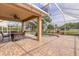 A covered brick patio features a ceiling fan, dining table and chairs, plus a screened-in pool with tranquil water view at 6950 Vintage Ln, Port Orange, FL 32128