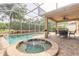 Screened pool and spa on a brick patio with landscaping and a view of the trees and pond at 6950 Vintage Ln, Port Orange, FL 32128