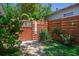 This backyard features a wooden fence with a welcoming gate, lush greenery, and manicured grass at 913 Palmetto St, New Smyrna Beach, FL 32168